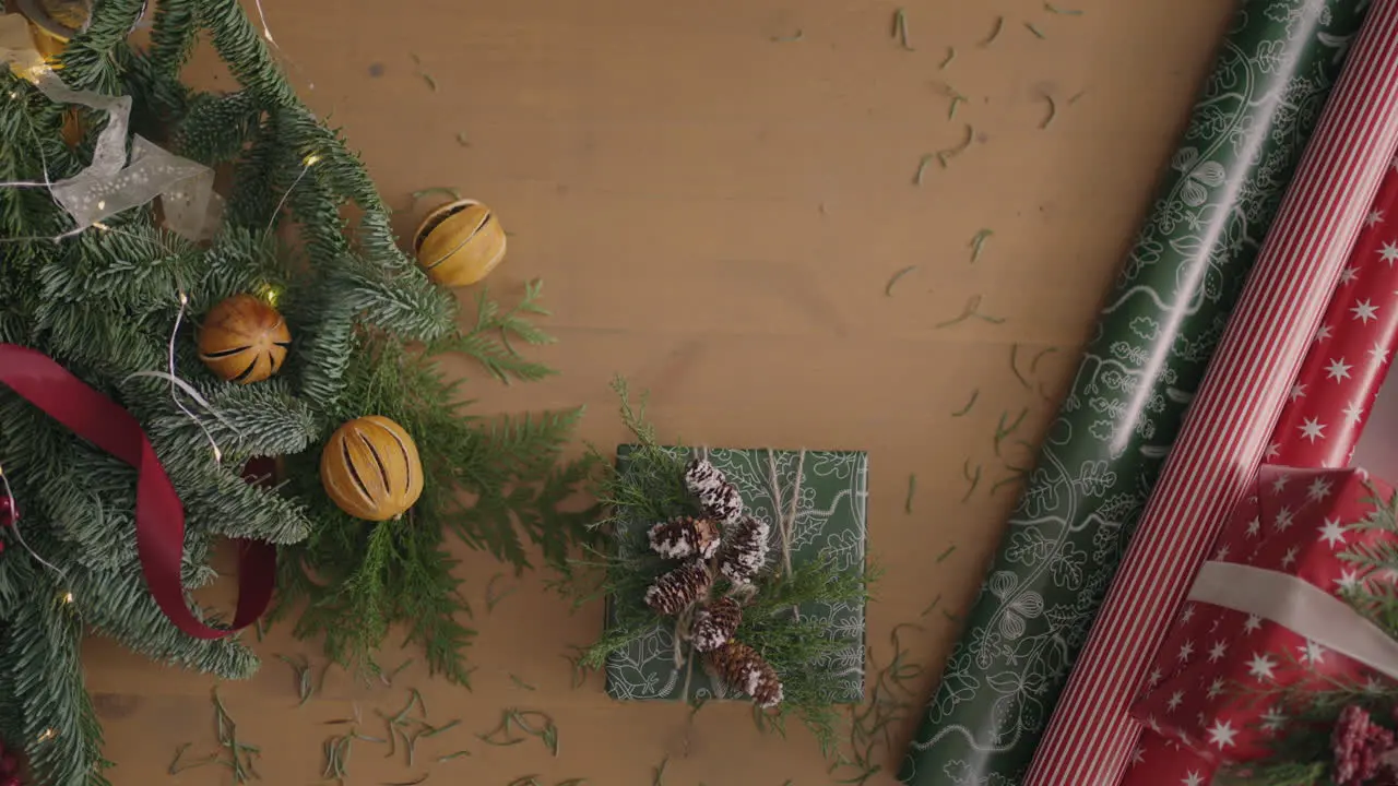 top view plan Fully visible the table with the decorations hands put and finalize Christmas gift wrapped in craftool paper on a wooden table Bandaging tape and tied bow