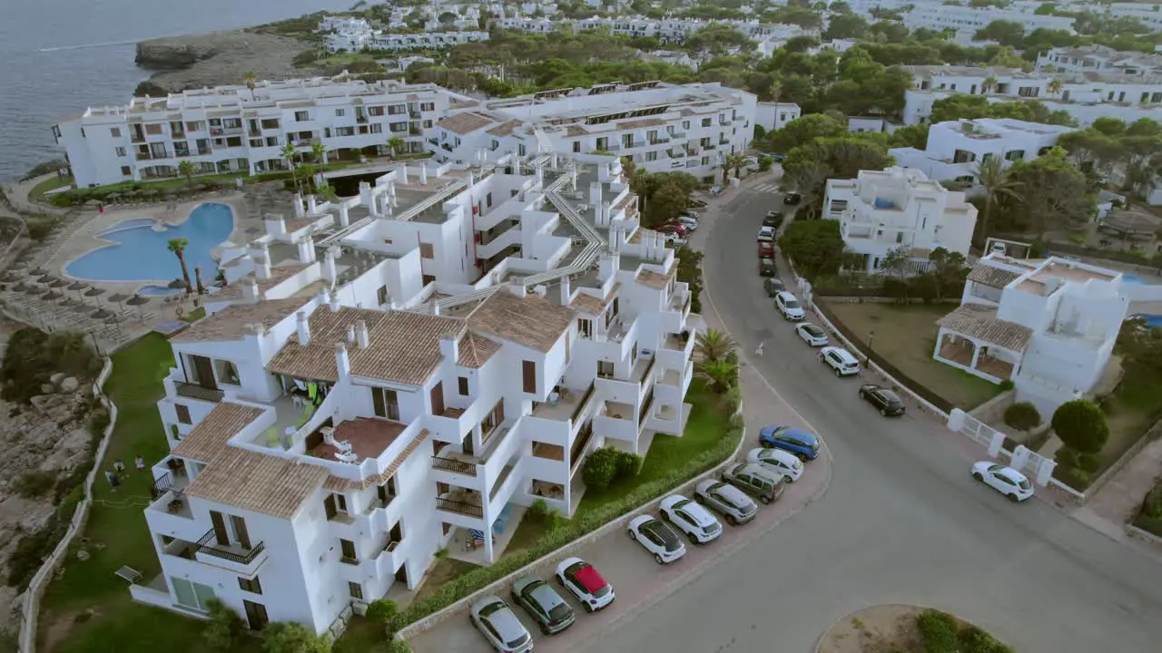 A rotating aerial view captures a complex of tourist accommodation buildings situated along the coastline of Mallorca Spain embodying the concepts of tourism and vacation