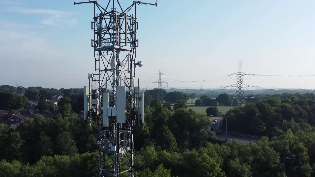 5G broadcasting tower antenna in British countryside with vehicles travelling on highway background aerial zoom out view