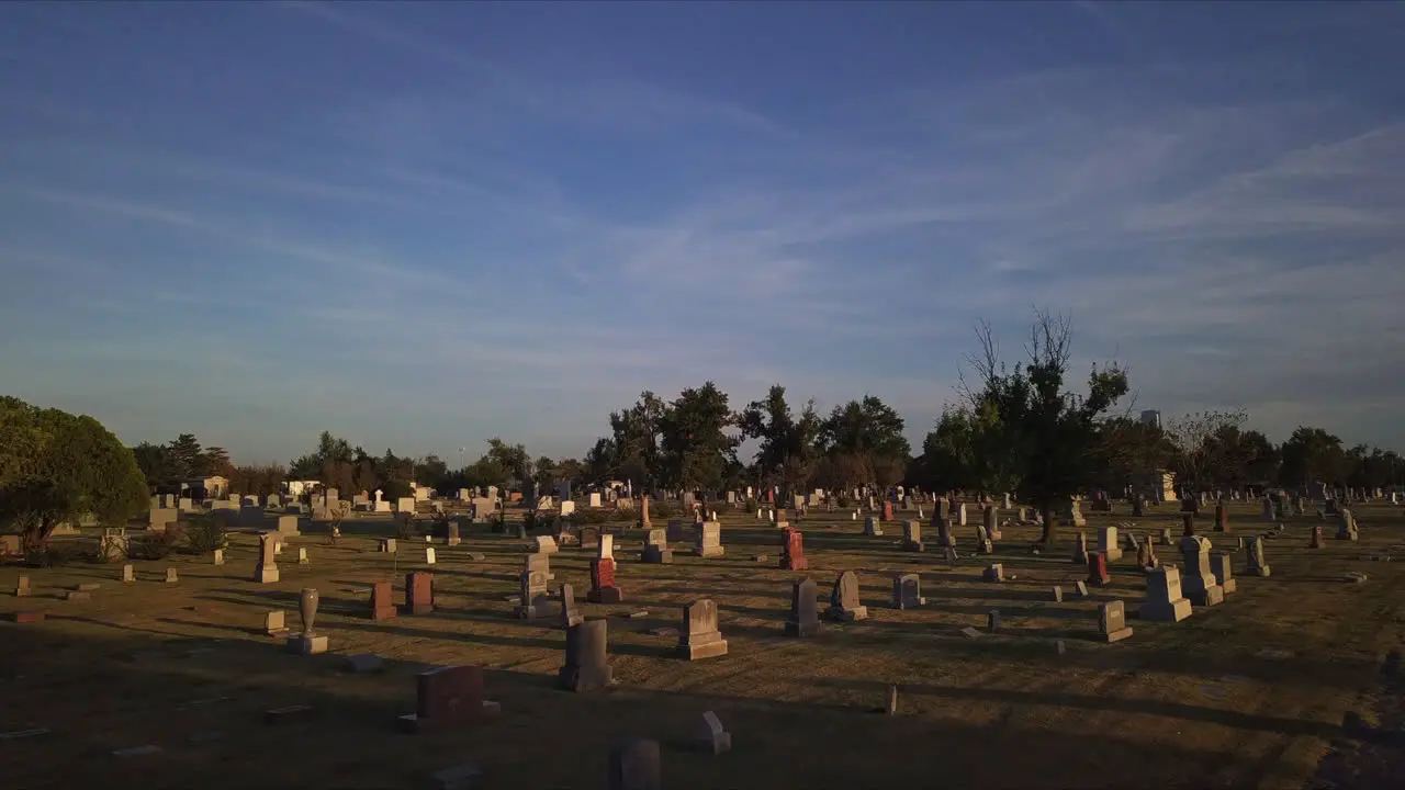 Slow aerial dolly through a graveyard at sunset