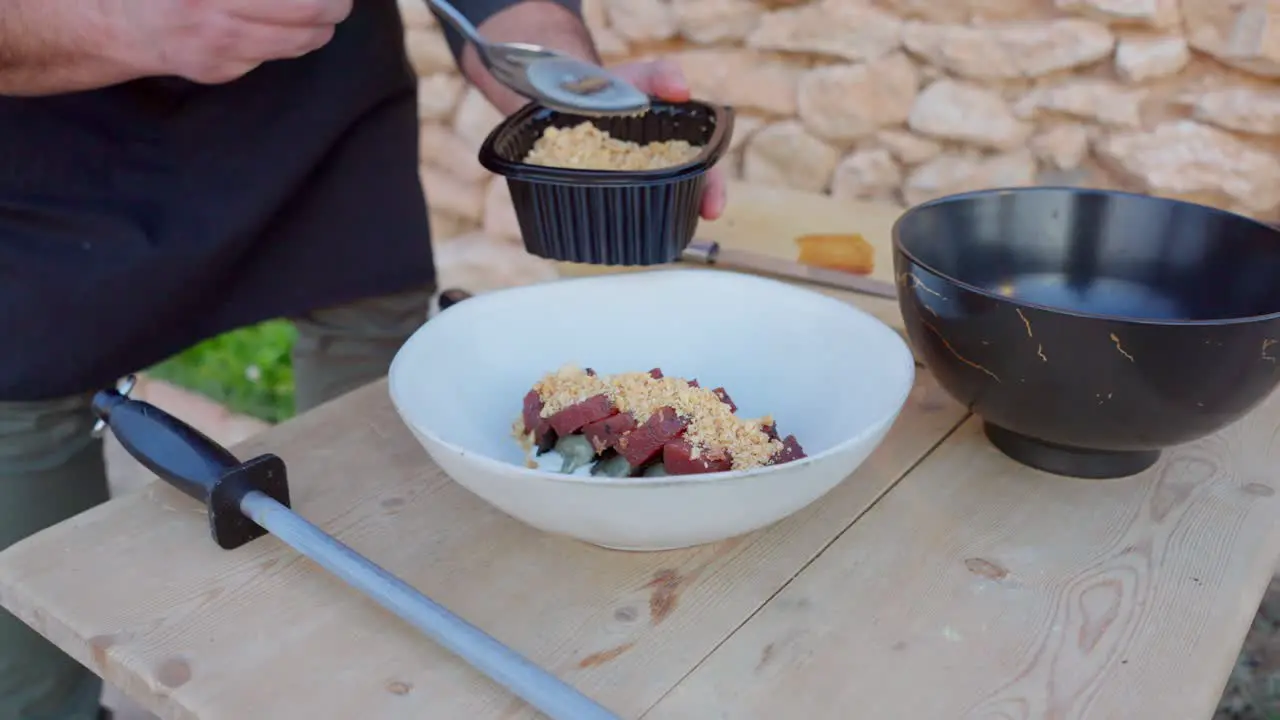 Chef prepares Mediterranean food with raw tuna and crushed almonds