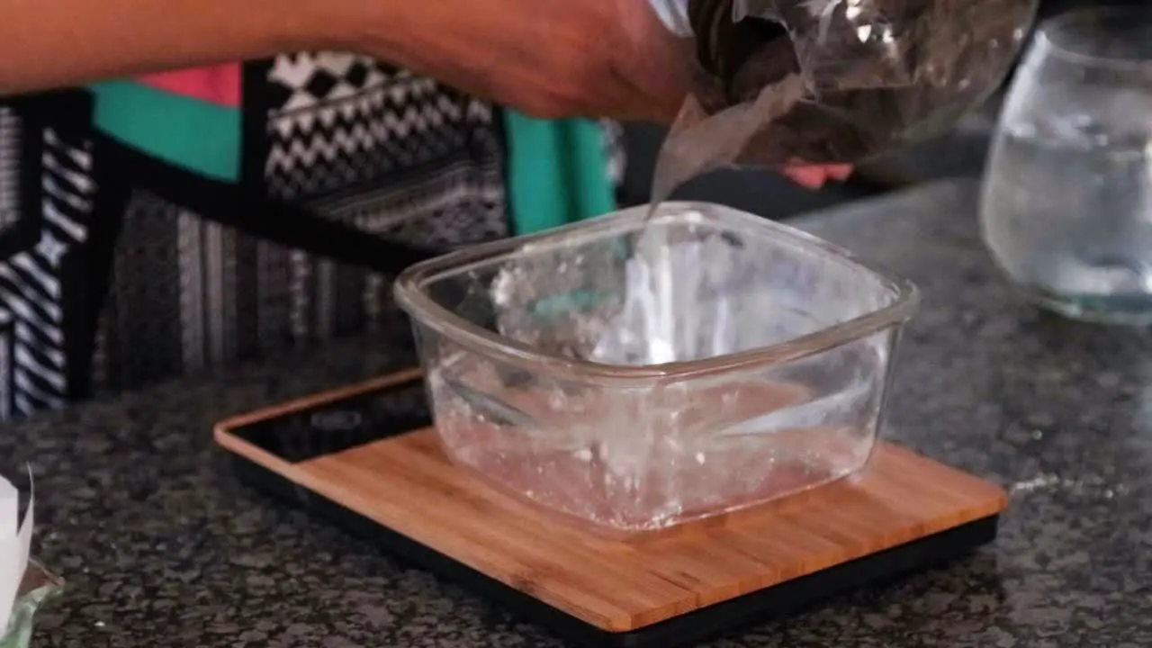 Weighing chocolate in a glass bowl on a bamboo scale