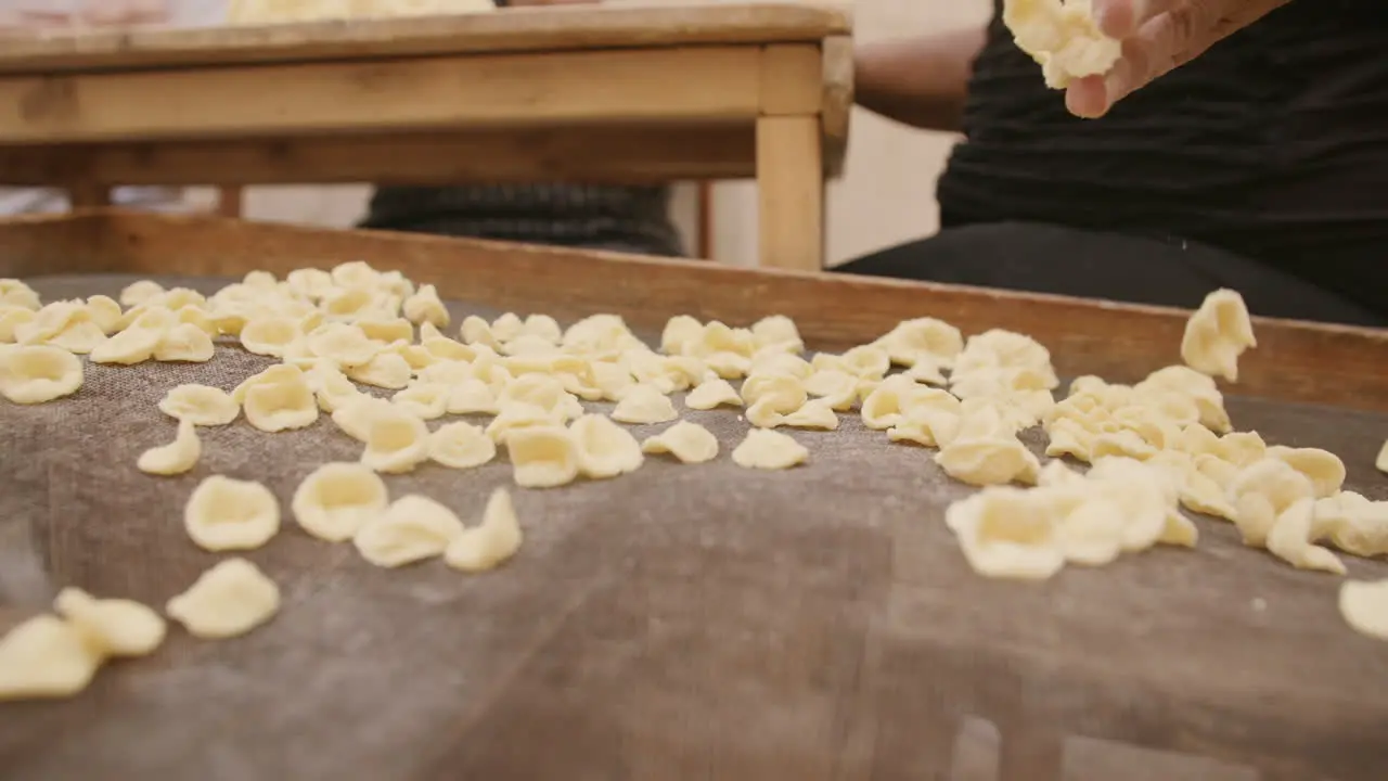 Close up slow motion footage of a lady throwing freshly made conchiglie shells onto a net