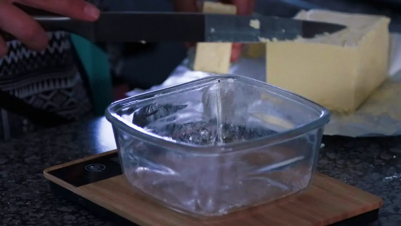 Weighing butter for brownies in a glass bowl on a bamboo scale