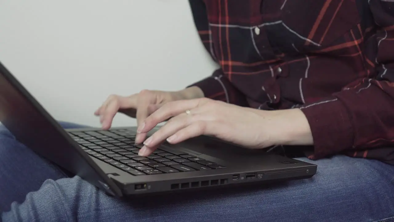 Female has laptop on her legs writing to her friends closeup