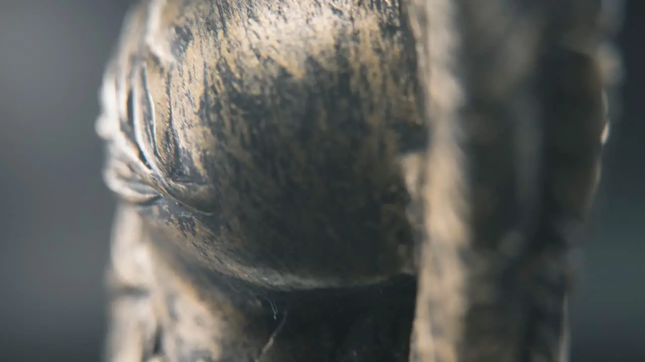 A close up macro detailed slow tilt up shot from behind of a spartan face design warrior ancient greek bronze helmet on a 360 rotating stand studio lighting 4K smooth movement