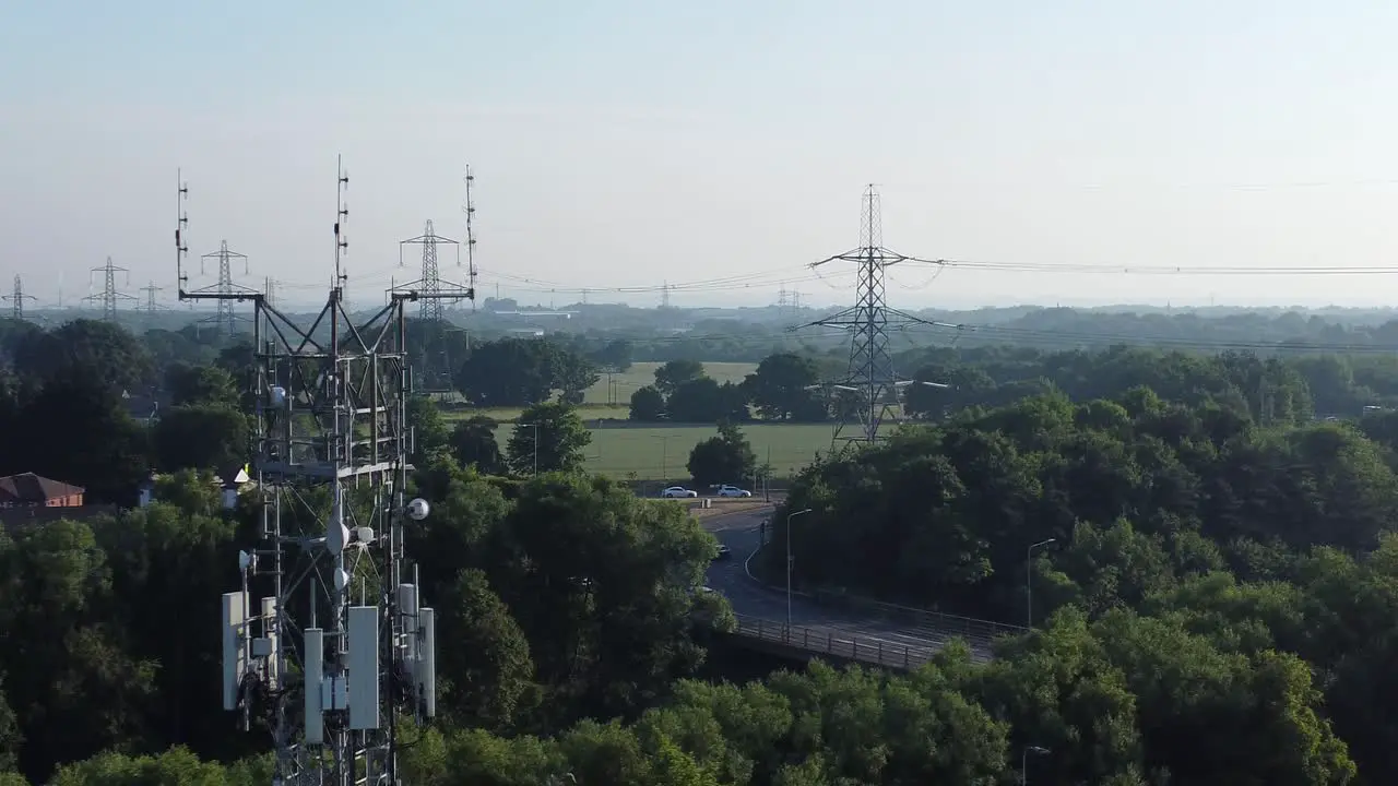 Aerial view 5G broadcasting tower antenna in British countryside with vehicles travelling on highway background rising right