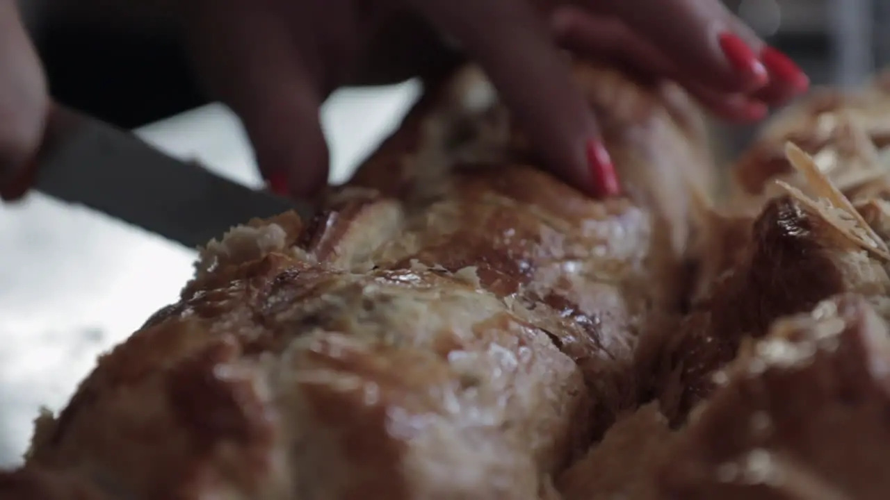 Woman cutting big sausage roll red nails