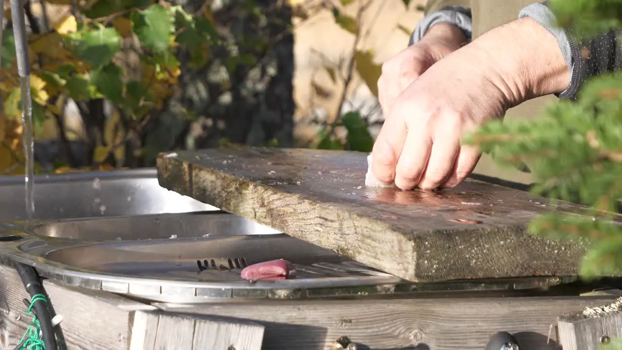 Close up of man processing and slicing fish fillet on outside preparation table