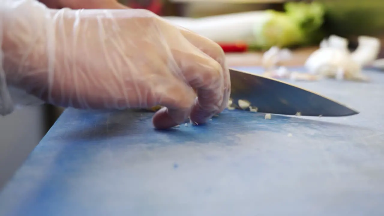 Cutting garlic into small pieces on a blue cutting board in a sushi restaurant