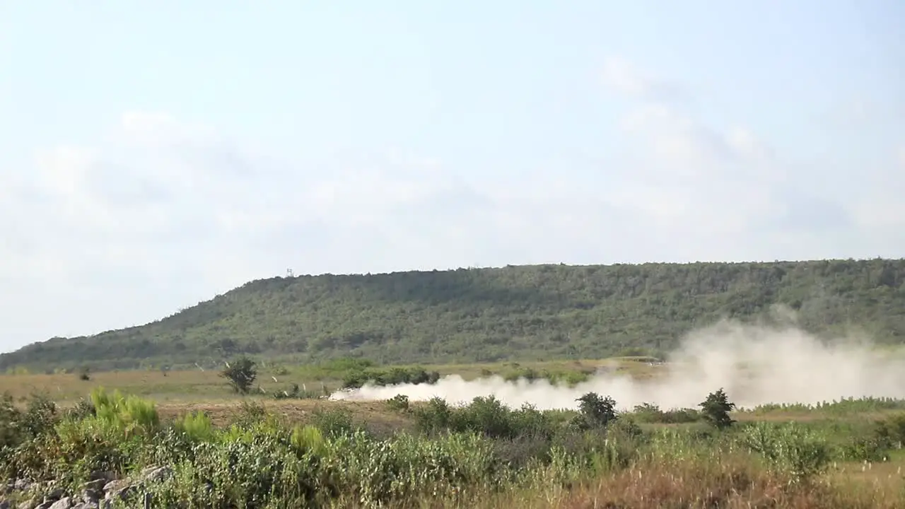 Military vehicle moving though training ground wide view