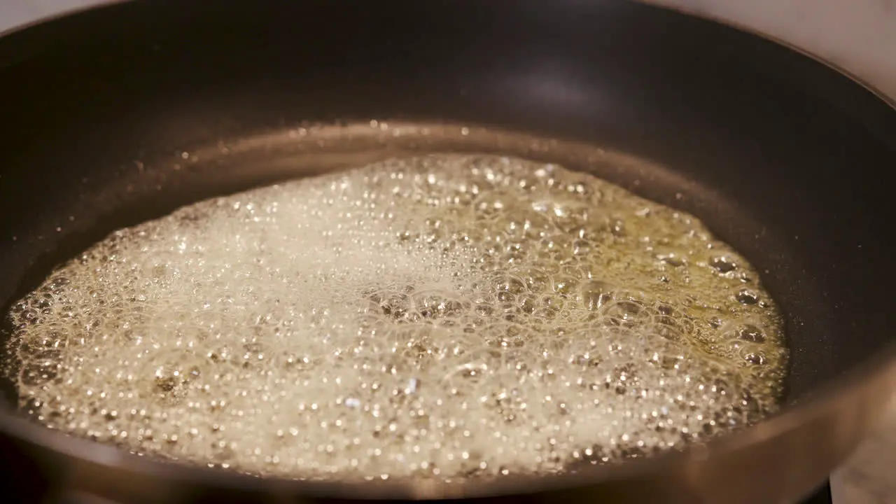 Close up of butter frying in a pan handheld