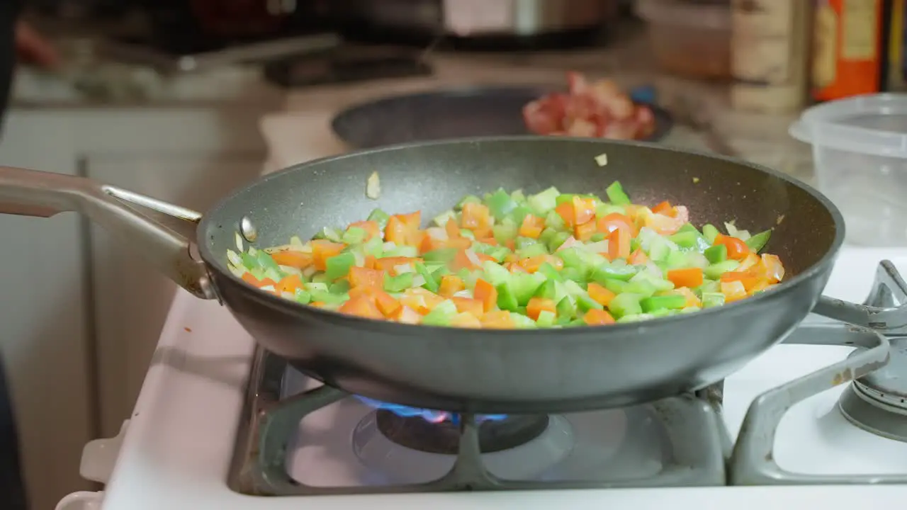 Diced vegetables cooking in a frypan on a domestic gas stove closeup