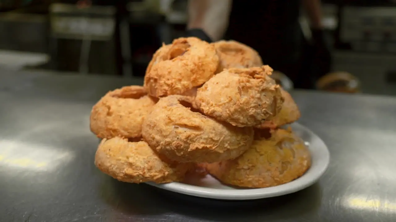 Deep fried onion rings piled high placed on pass by cook HD