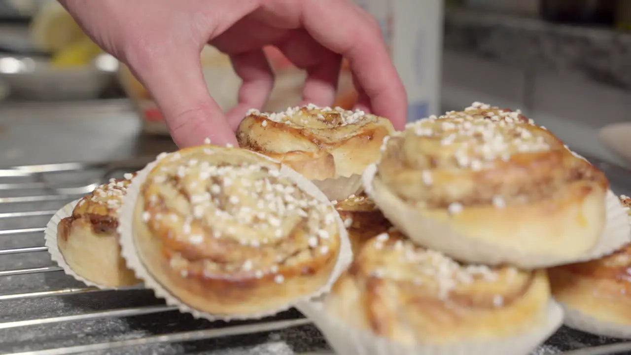 Male hand picking up a cinnamon bun in the background