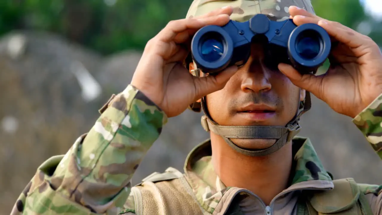 Front view of young caucasian military soldier observing on field during military training 4k