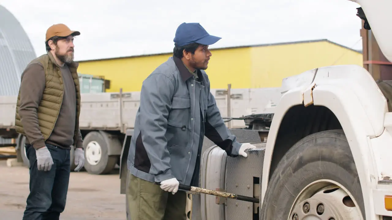 Worker Fixing A Truck In A Logistics Park While Being Supervised By His Boss