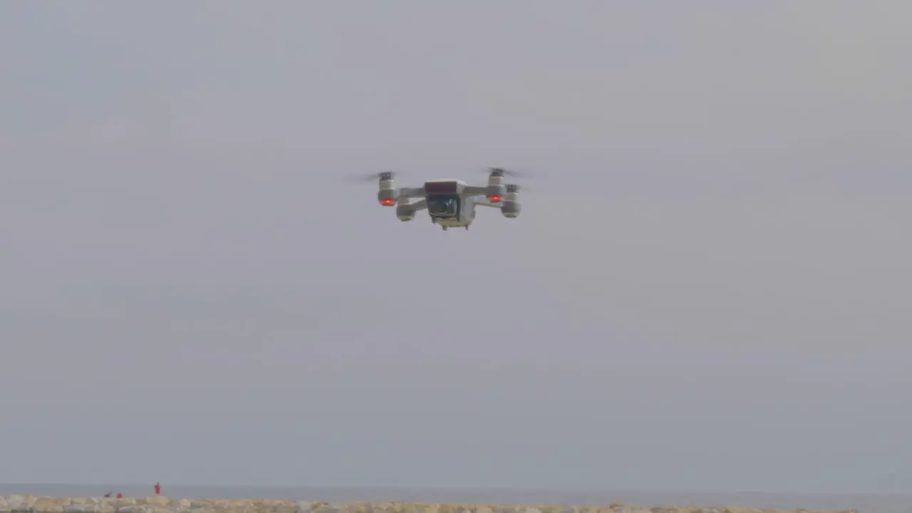 A closeup view of a flying drone camera blinking lights and turning at the beach