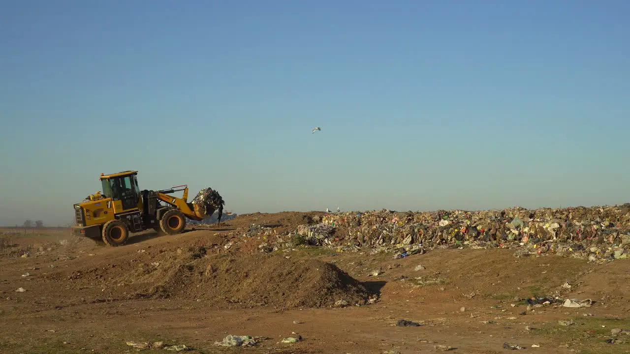 A bulldozer enters a dumping ground loaded with waste