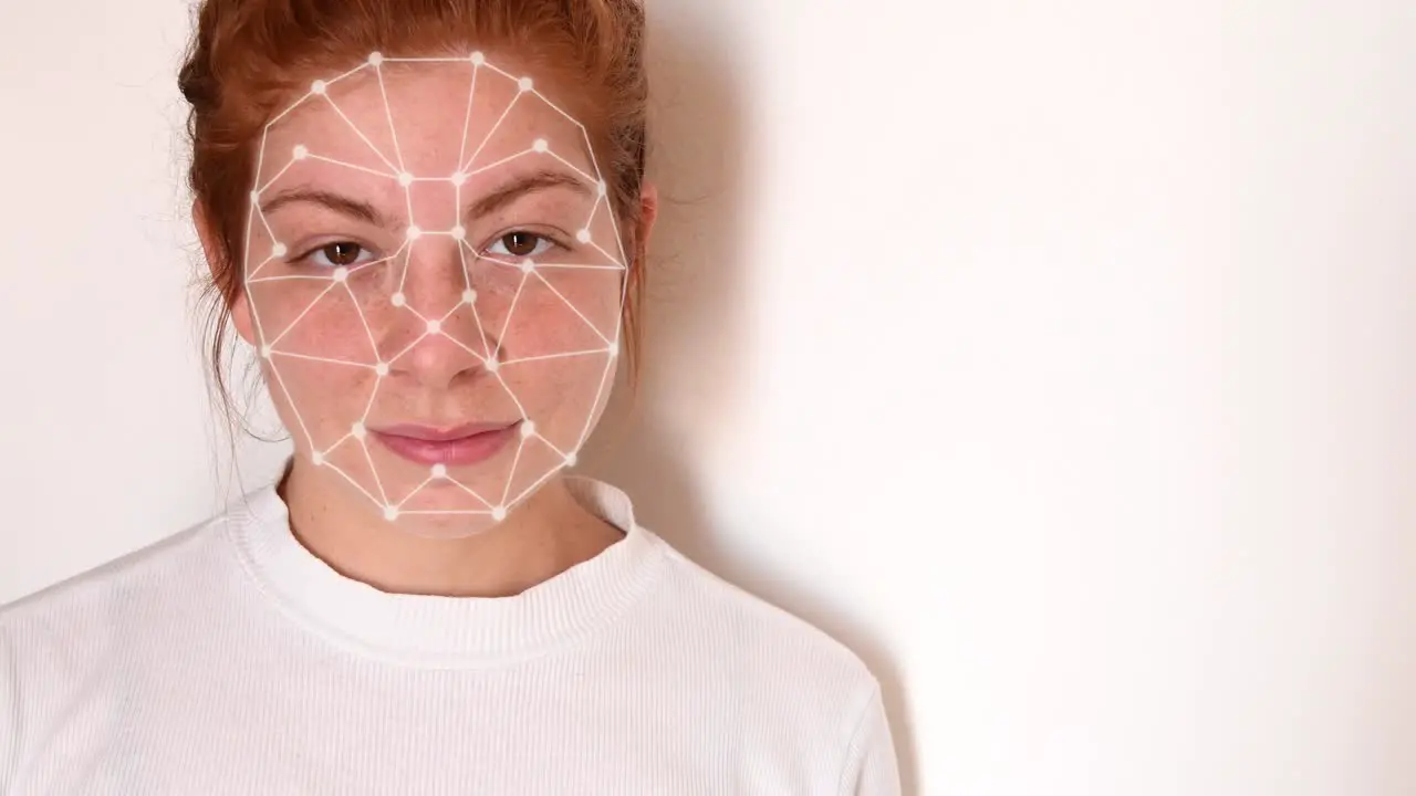 Close up of a young woman with red hair with a white shirt on a white background with facial recognition high tech animation with tracking points and a glow effect on her face