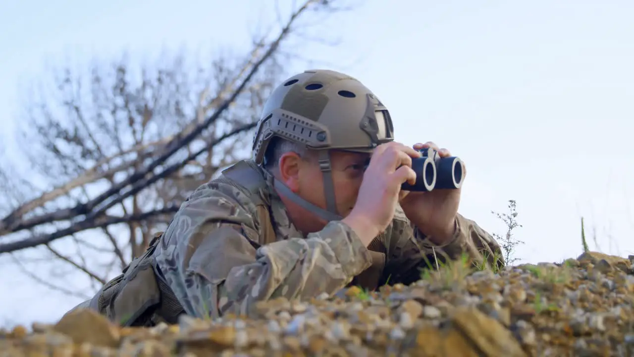 Side view of military soldier looking through binoculars during military training 4k