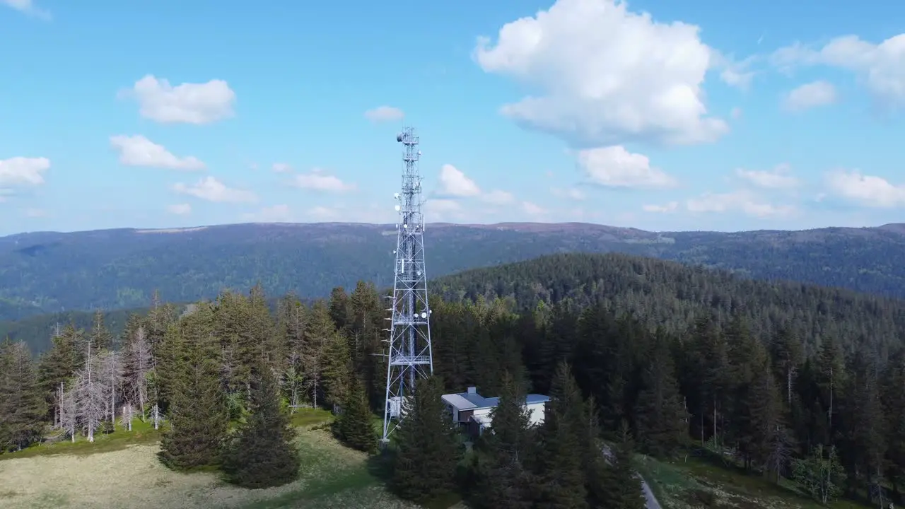 Aerial orbit view around a tall telecommunication antenna mast pylon among mountain forest in Sérichamp Vosges France 4K