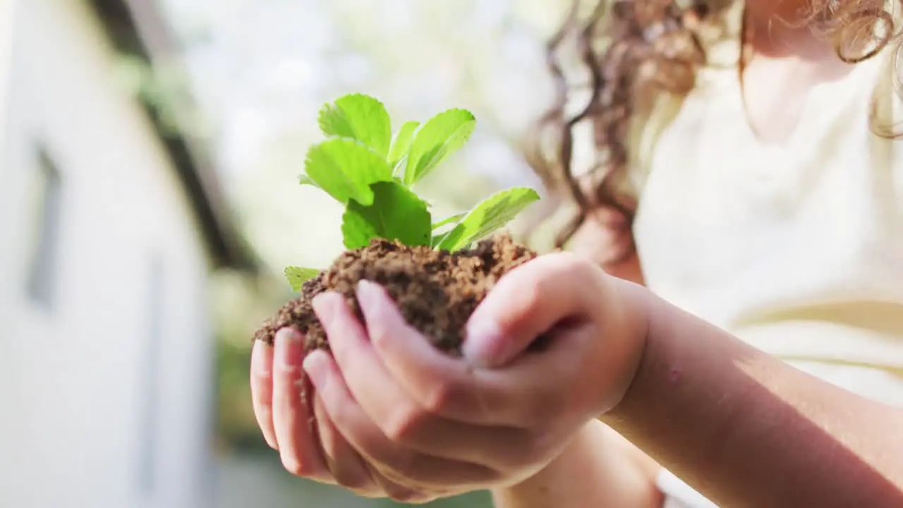 Mixed race mother and daughter gardening in sunny garden taking care with plants