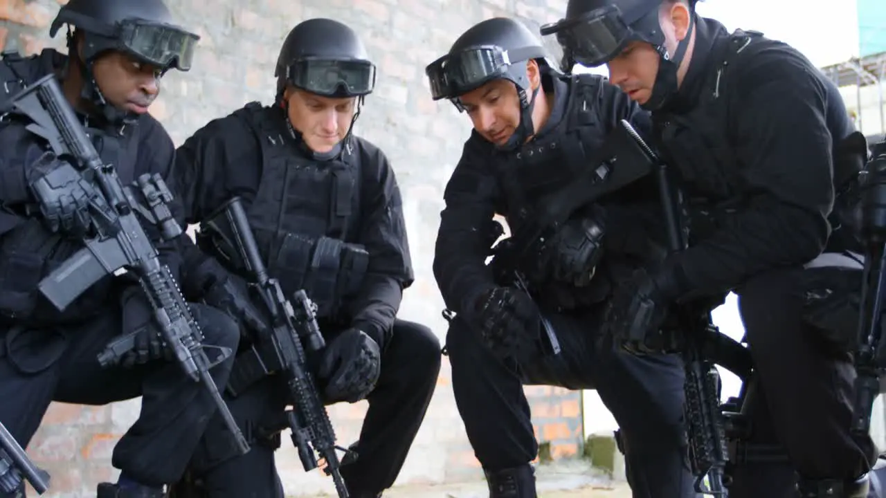 Side view of mixed-race military soldiers with rifles planning and crouching on floor at base 4k