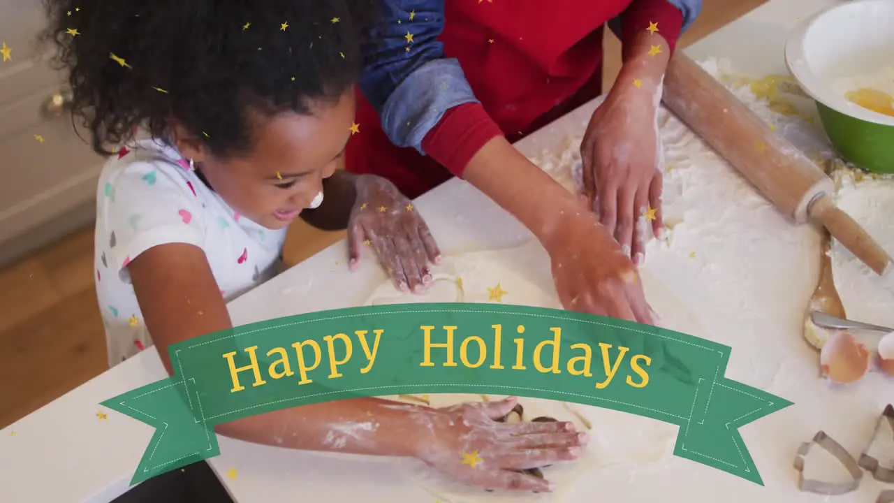 Animation of happy holidays over happy african american daughter making cookies with mother