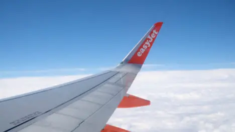 View From Plane Window Of Blue Sky And Clouds On Flight To Summer Holiday Vacation