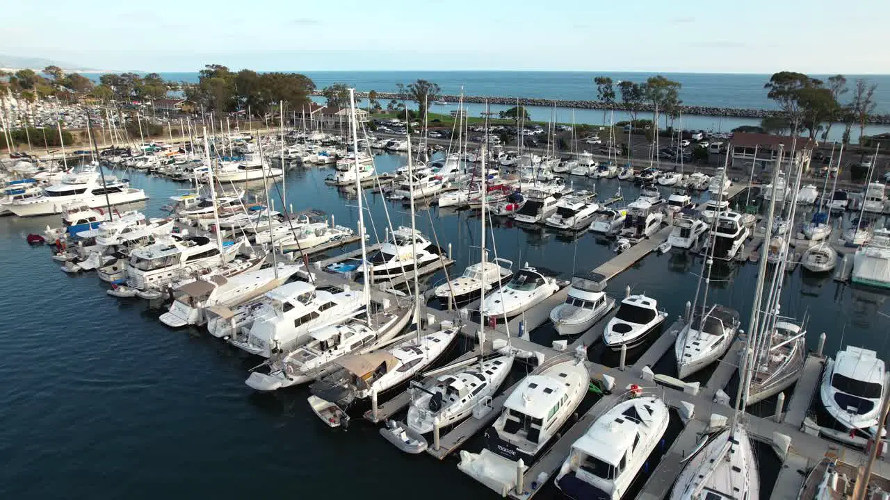 Luxury sailboats moored at Dana Point Marina with Pacific Ocean in Backgound Aerial ascending view