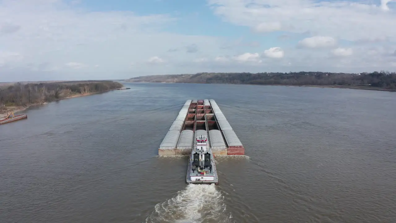 Aerial close-up panning shot of a river barge transporting goods on the Mississippi River