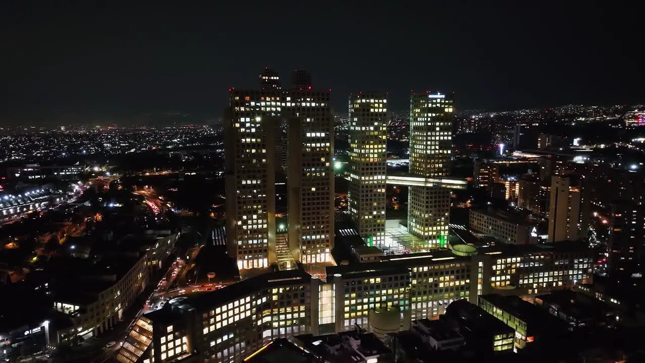 Aerial view away from the Arcos Bosques complex nighttime in Mexico city pull back drone shot