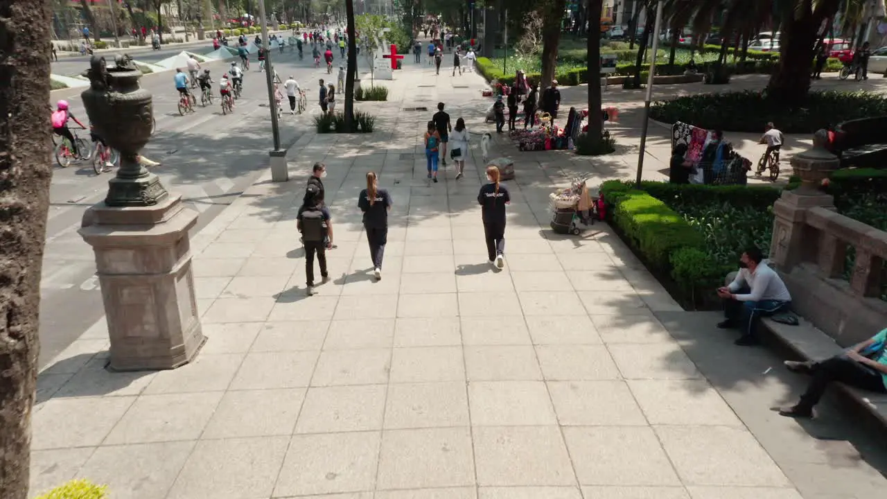 Aerial low angle above people walking at sidewalk cyclists in background