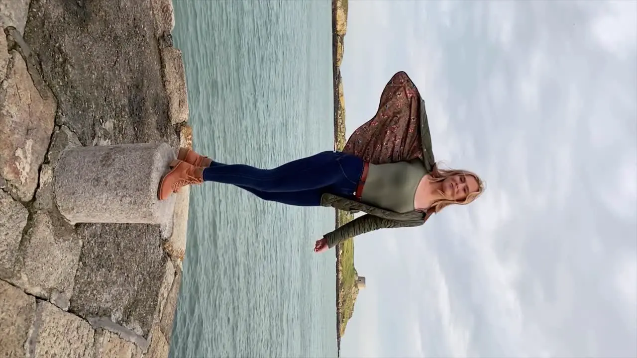 An attractive young woman turns to camera revealing the Irish coastline