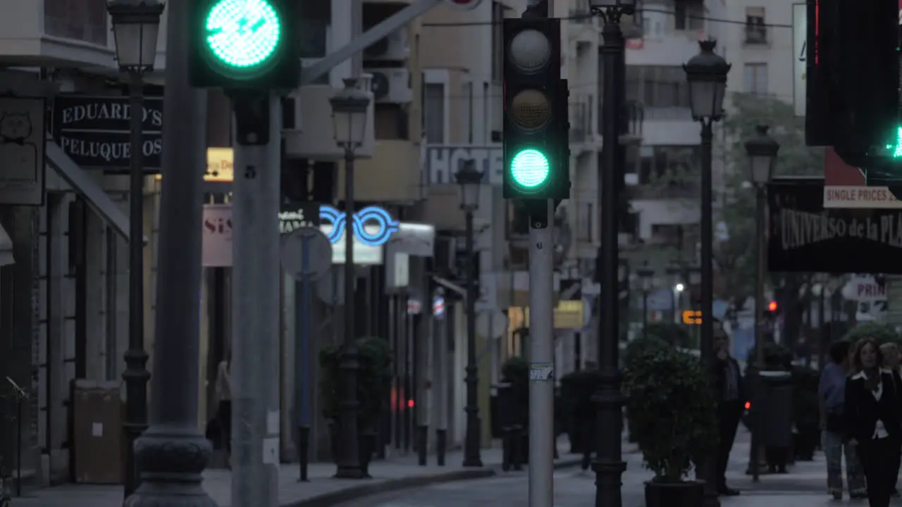 Evening street with stores walking people and transport traffic Spain