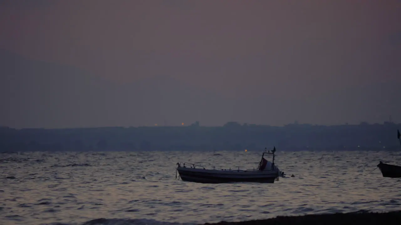 Evening scene of sea with moored boat rocking on waves