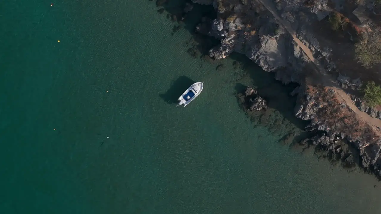 Top down aerial shot over a small stationary boat in clear water