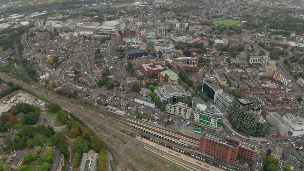 Aerial shot over high speed train passing through Watford Junction station looking towards Watford town