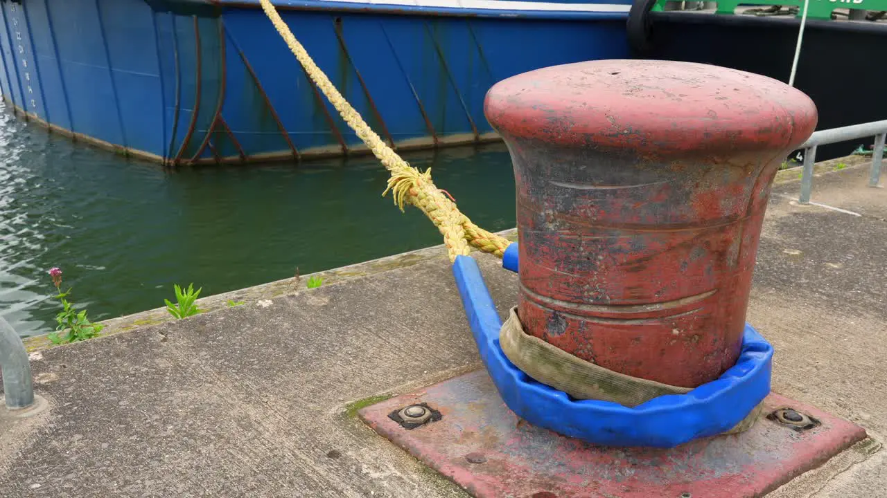 Mooring post for boat in harbour seafront yellow rope blue boat