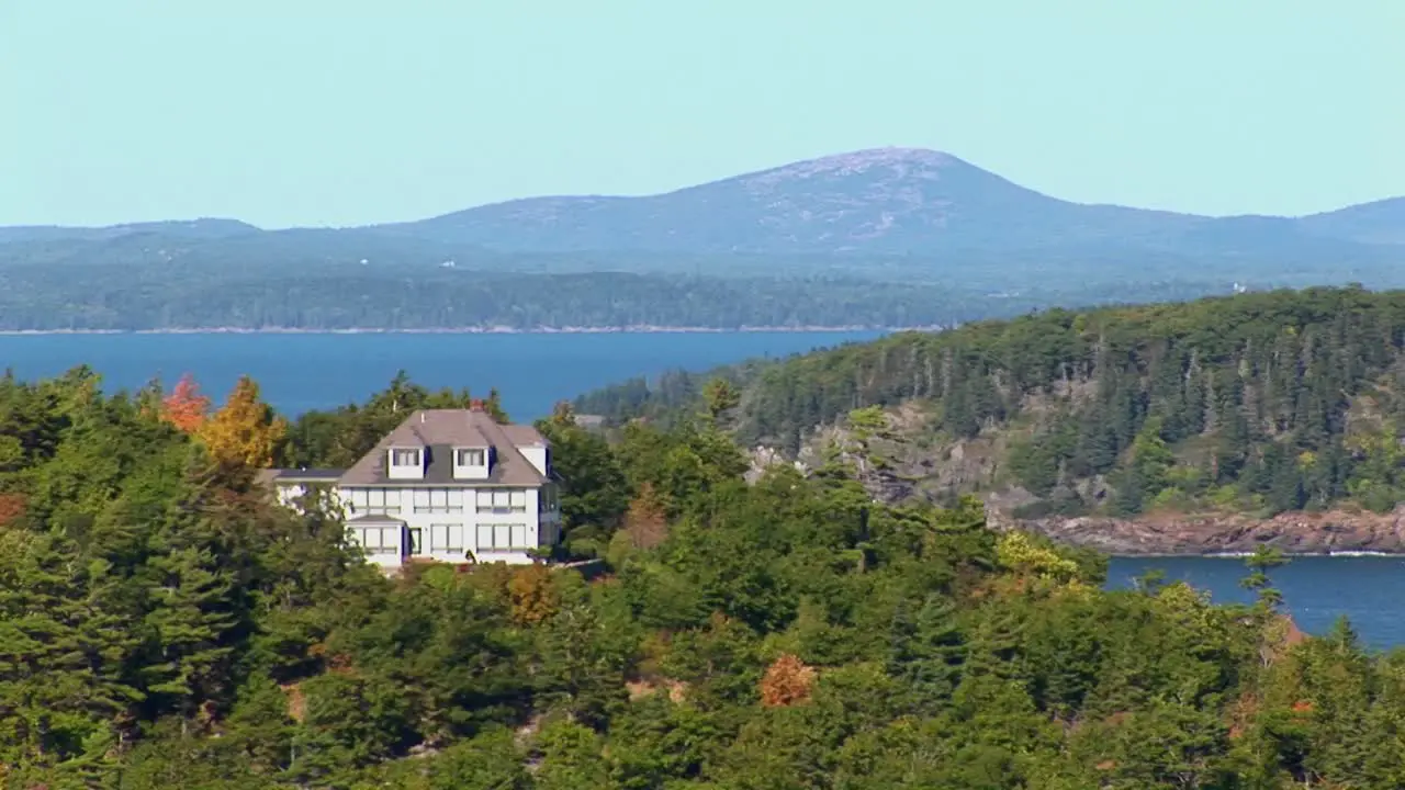 A house and islands are seen in the distance of a forest in Bar Harbor Maine