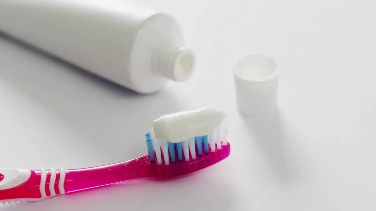 Video of close up of toothbrush and paste on white background