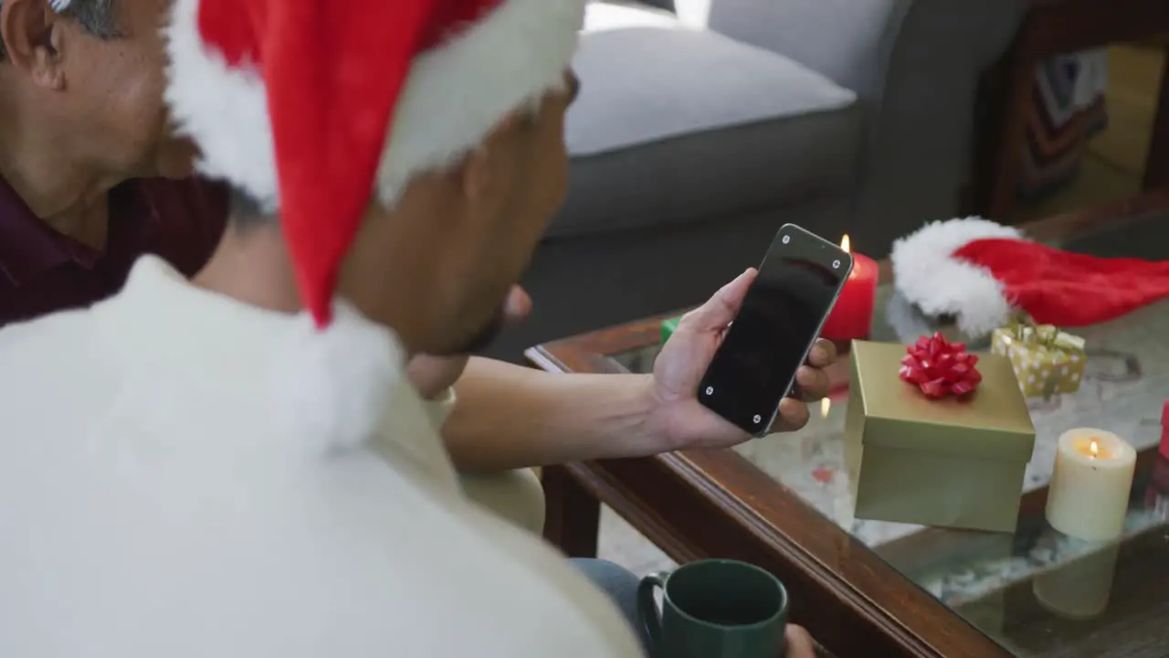 Son and father making christmas video call on smartphone with blank screen and copy space at home