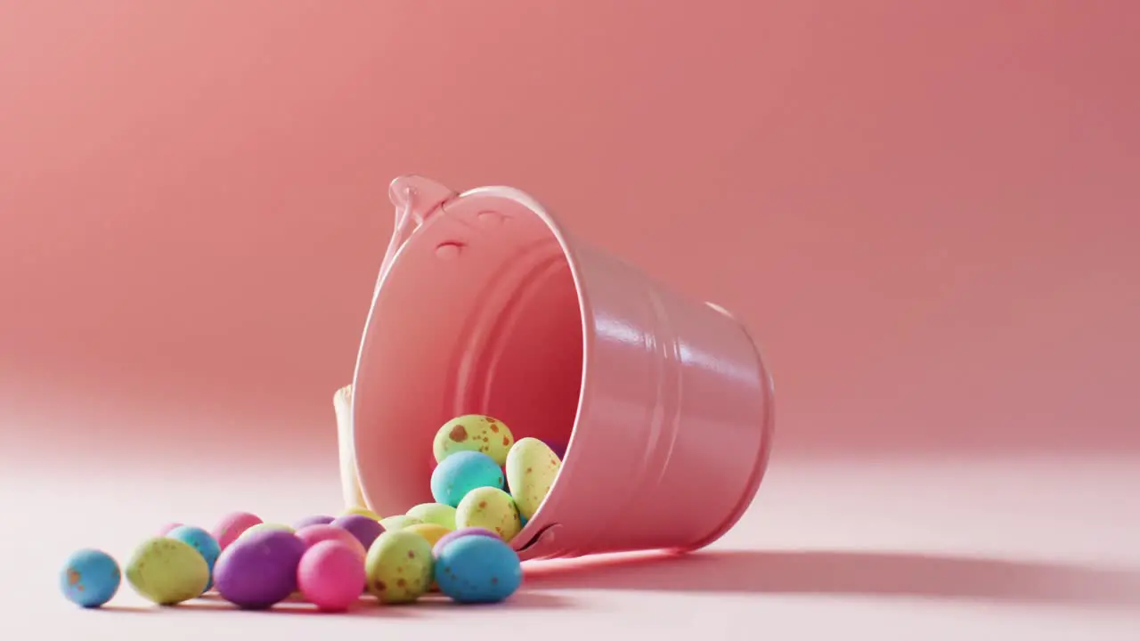 Bucket with colorful easter eggs on pink background with copy space