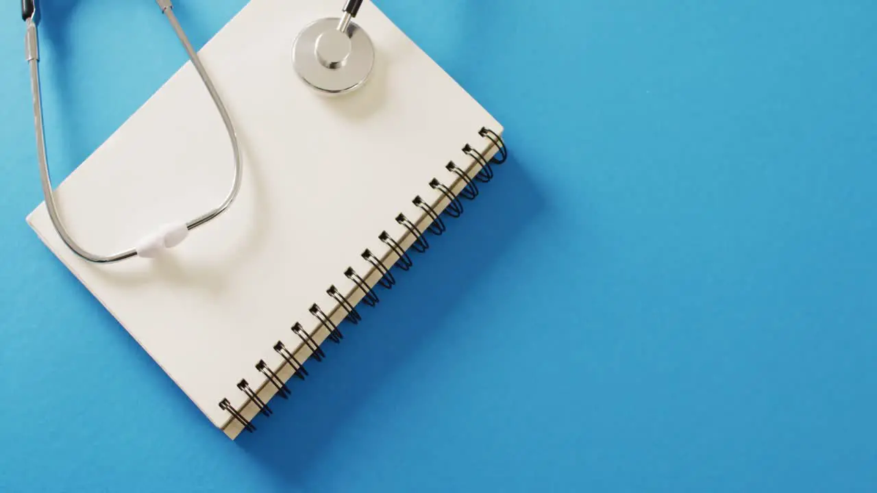 Video of stethoscope on notebook on blue background with copy space