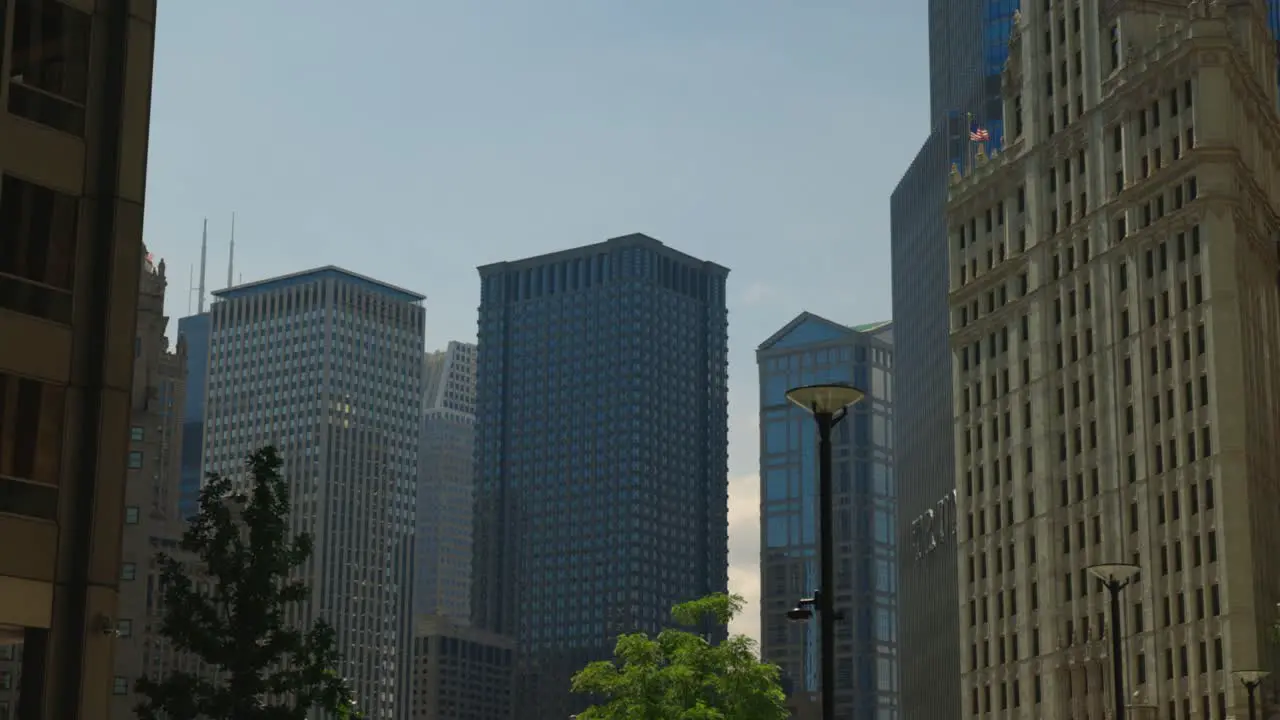 Cluster of tall buildings in the city stand tall in the blue sky as a bird flies through the frame