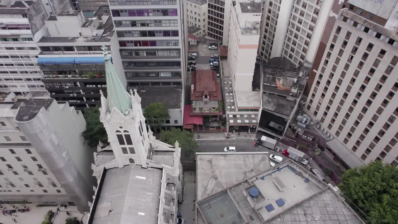 Urban aerial pulls up from old building surrounded by tall skyscrapers