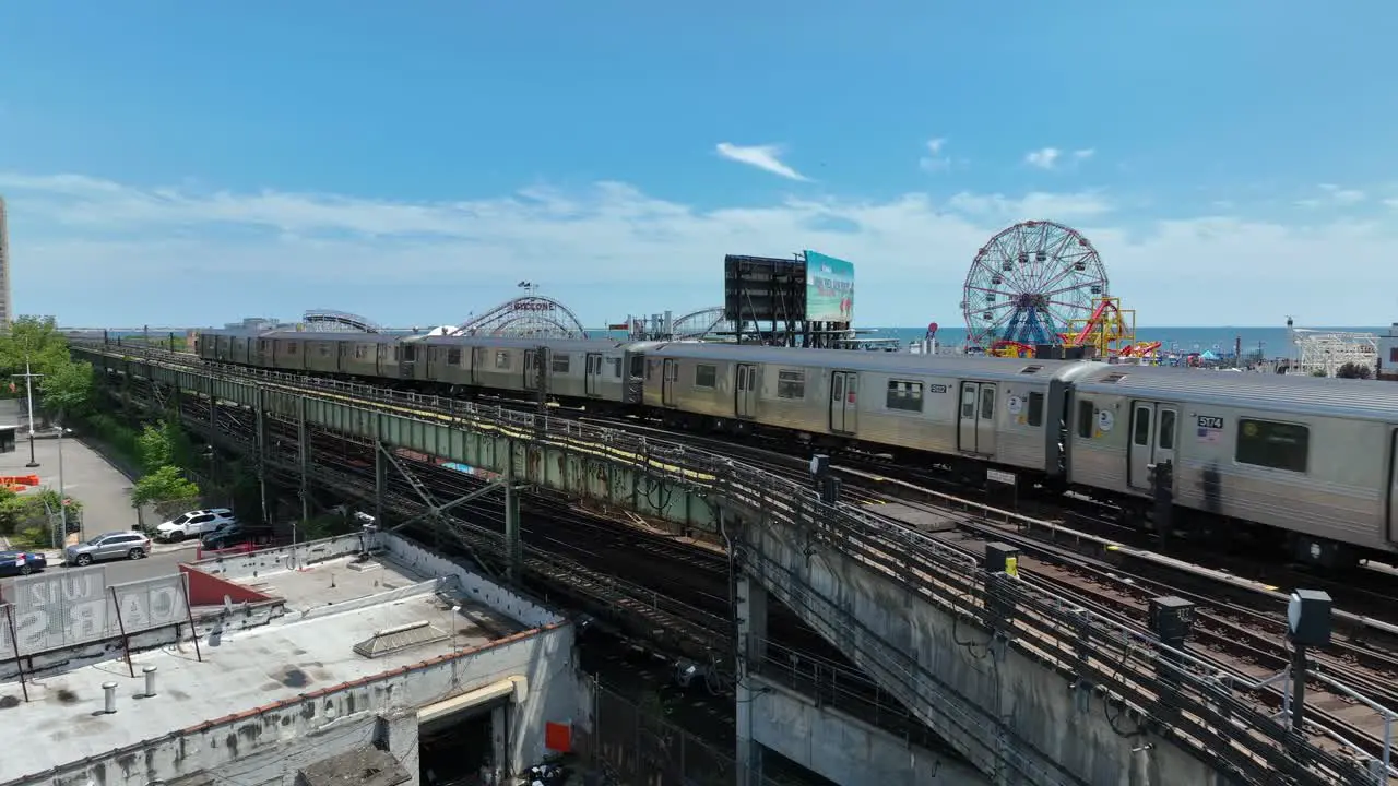 Aerial shot of NYC commuter train running on tracks in front of Coney Island amusement park