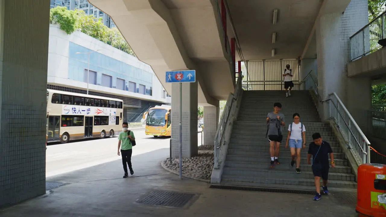 Asian people walking downstairs from bridge in City Downtown of Hong Kong in summer orbit shot