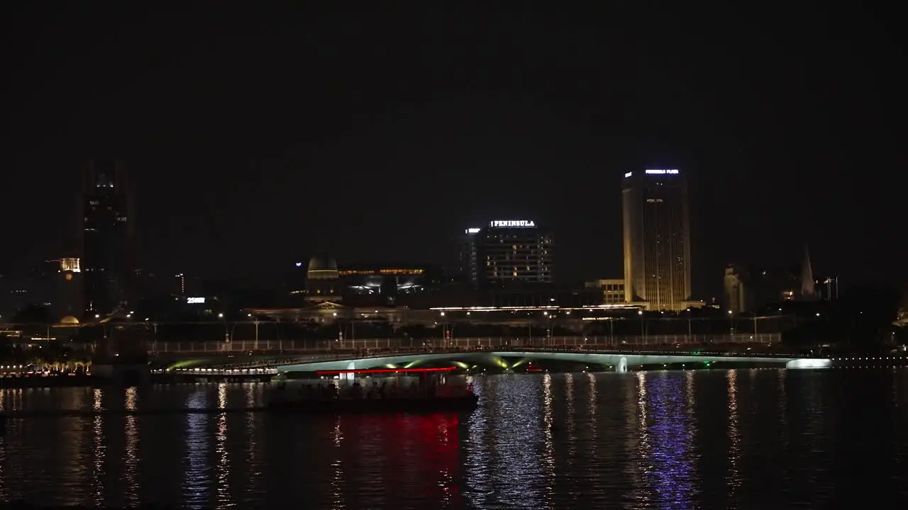 Night time cityscape of the Marina Bay with the Jubilee Bridge in Singapore city and transport boats passing by